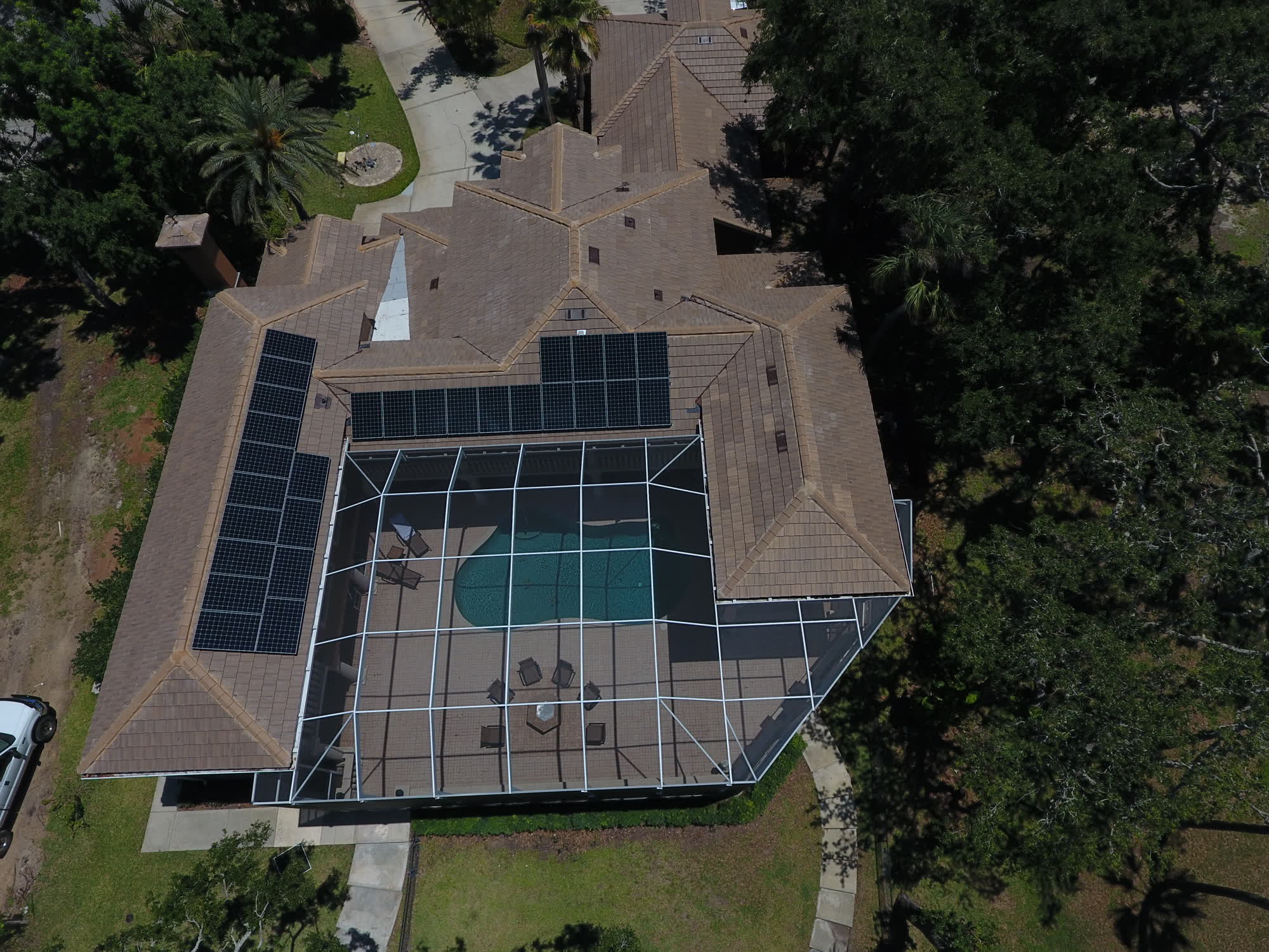 Aerial view of a Solar-Fit customer's home with rooftop solar panels over a screened pool